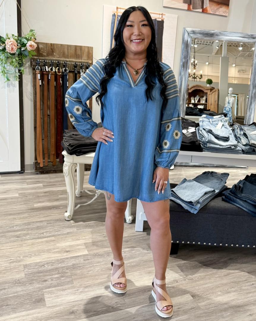 This Apricot Aztec Embroidered Denim Dress features a relaxed fit and mini length shift silhouette. It boasts a flattering V-neckline and long balloon sleeves adorned with a beautiful embroidered Aztec design. Perfect for warmer days. Finish the look with ankle boots, chunky heel sandals, or even cowboy boots.